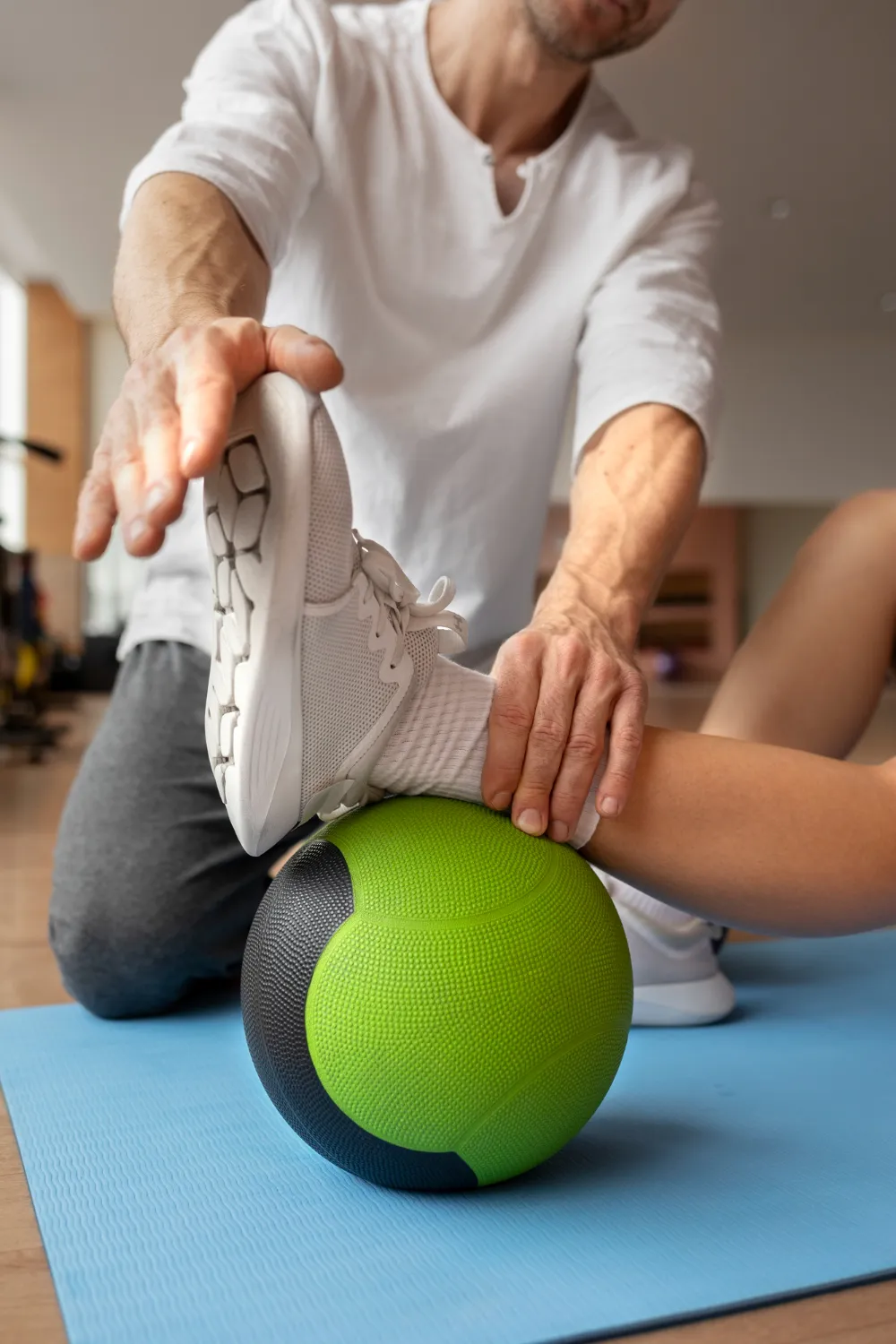 Physical therapist stretching a male athlete’s leg during a sports medicine rehabilitation session.