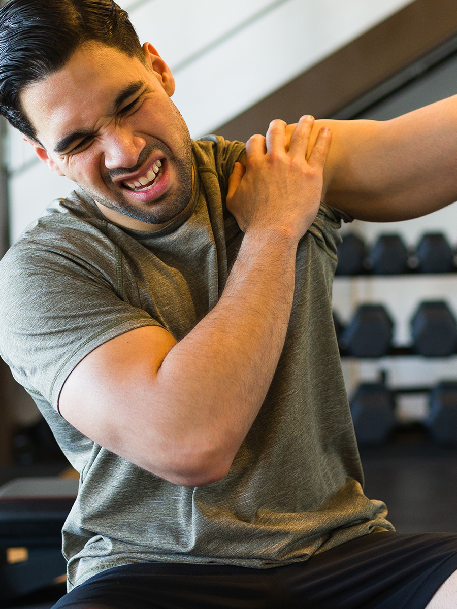 Man at the gym holding his shoulder in pain