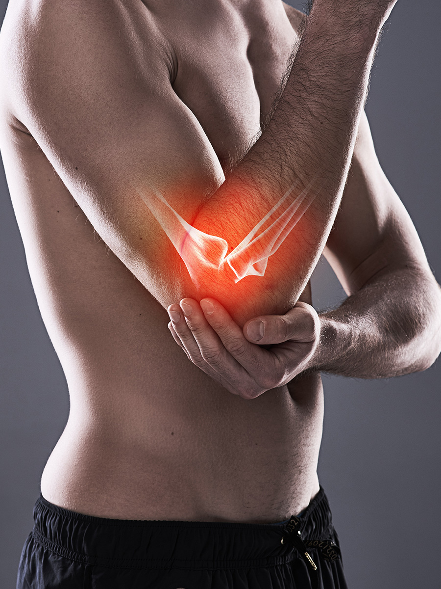 A shirtless man holding his elbow in pain
