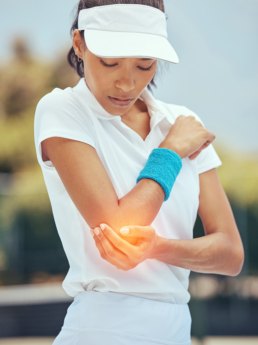 Woman playing tennis holding her elbow in pain