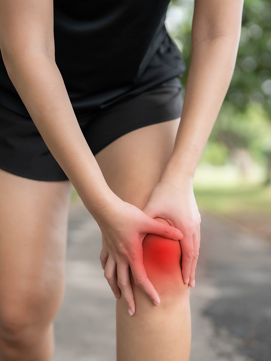 Woman outdoors holding her knee in pain