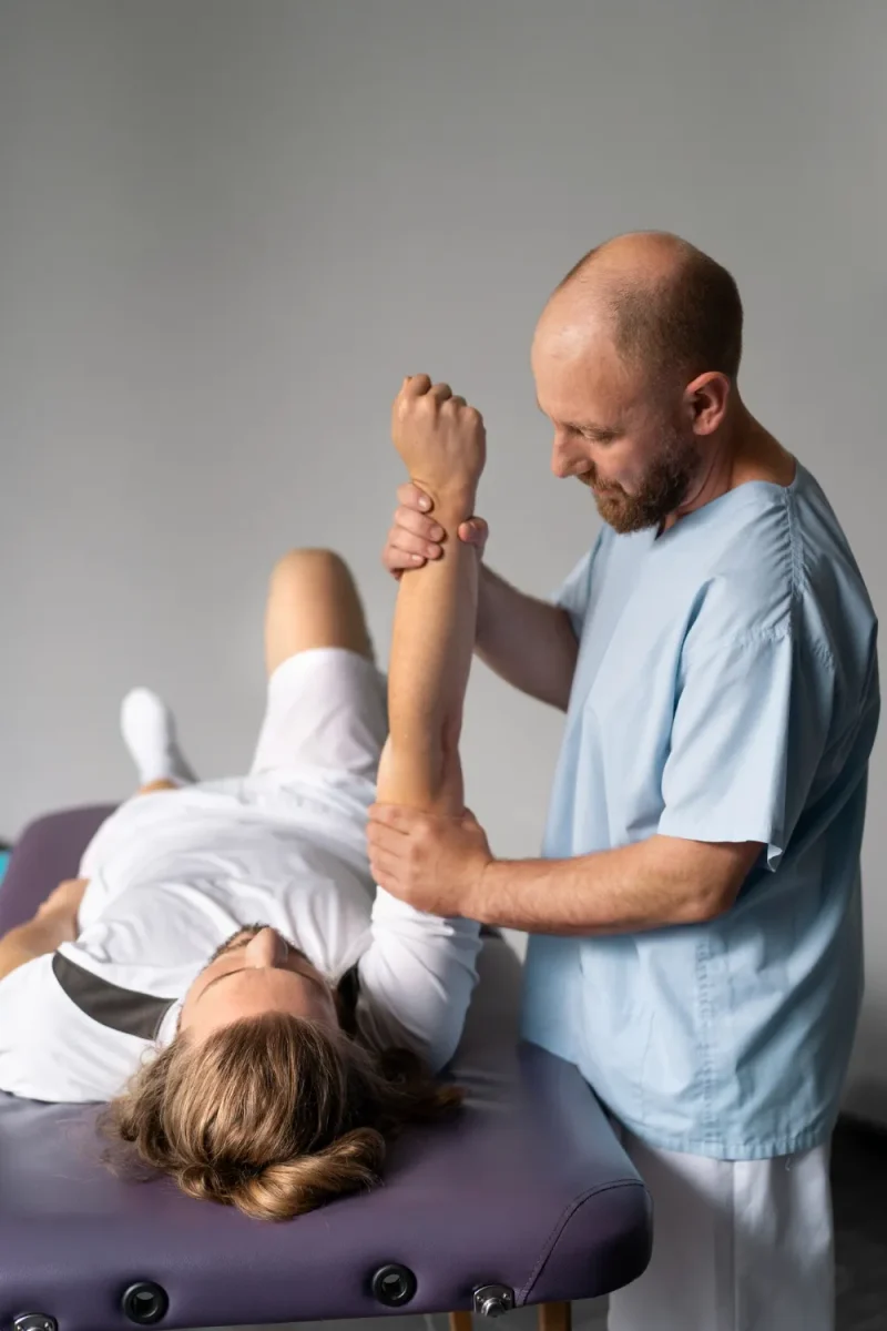 Physical therapist performing assisted shoulder mobility exercise on a patient lying on a treatment table at Kerlan-Jobe Orthopaedic Clinic.